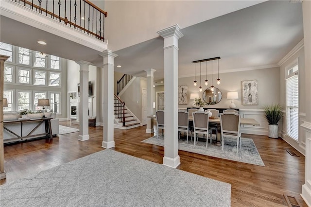 foyer entrance with stairway, ornamental molding, wood finished floors, and decorative columns