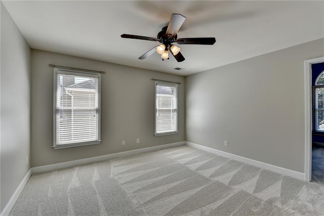 spare room featuring baseboards, light colored carpet, and ceiling fan