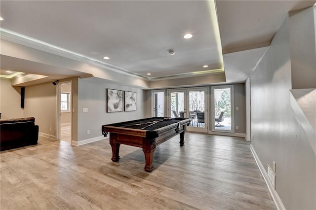 recreation room with a raised ceiling, french doors, light wood-type flooring, and a wealth of natural light