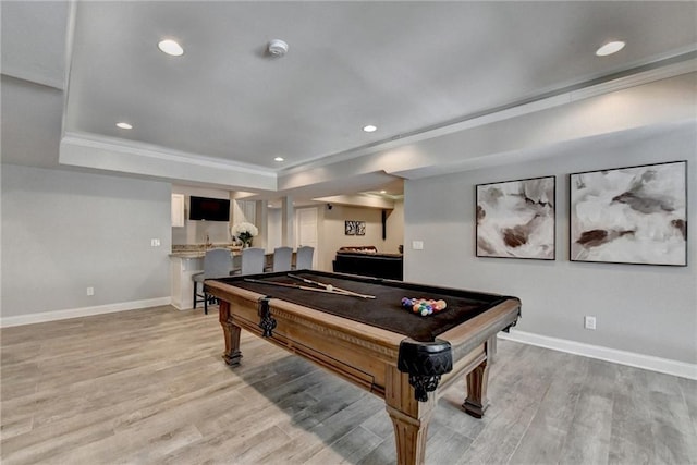 game room featuring baseboards, a tray ceiling, ornamental molding, recessed lighting, and light wood-style flooring