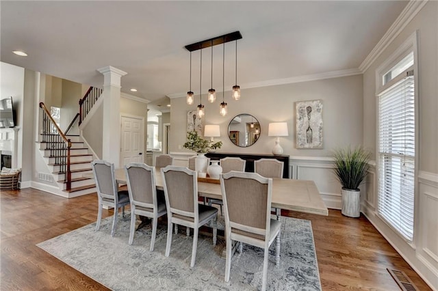 dining area featuring stairway, a wainscoted wall, visible vents, and wood finished floors