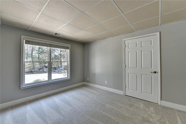 spare room featuring a drop ceiling, baseboards, and carpet floors