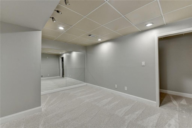 basement featuring carpet flooring, visible vents, baseboards, and a drop ceiling