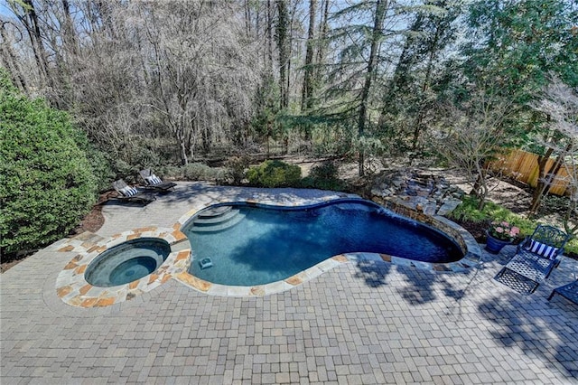 view of pool with a pool with connected hot tub, a patio, and fence