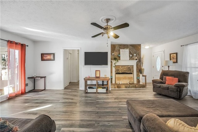 living room with ceiling fan, hardwood / wood-style floors, a textured ceiling, and a fireplace