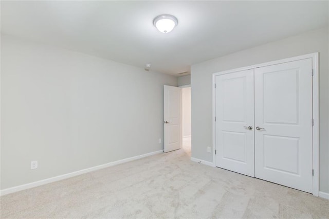 unfurnished bedroom with light colored carpet and a closet