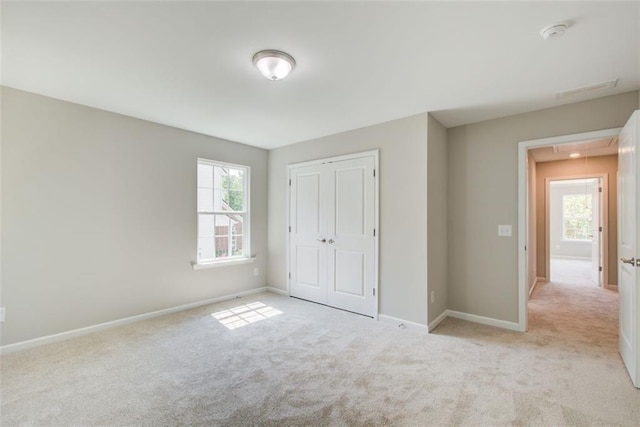 unfurnished bedroom featuring light carpet and a closet