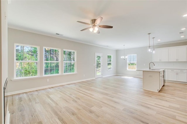 unfurnished living room featuring crown molding, sink, ceiling fan with notable chandelier, and light hardwood / wood-style flooring