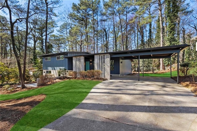 mid-century modern home with driveway, board and batten siding, and a front yard