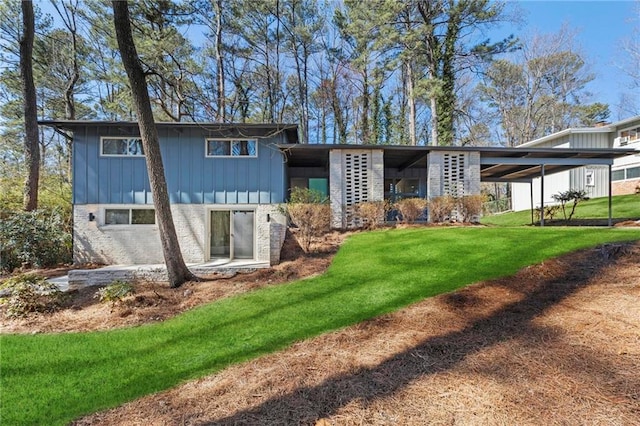 rear view of property featuring brick siding, a lawn, and board and batten siding