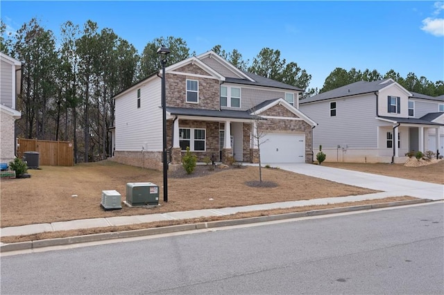 craftsman house featuring stone siding, fence, cooling unit, concrete driveway, and a garage