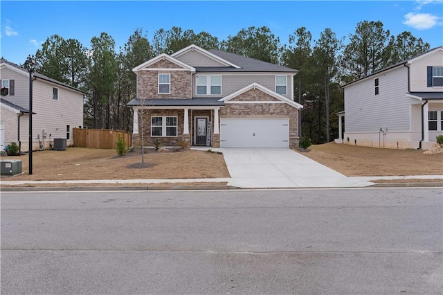 craftsman-style house featuring driveway, stone siding, fence, a garage, and central AC unit