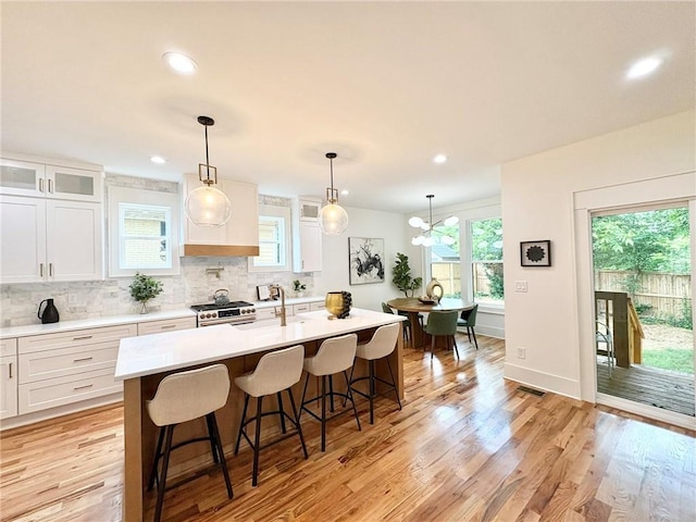 224 Cambridge Ave, Decatur, GA 30030 - kitchen featuring a center island with sink, stainless steel gas range oven, a sink, light countertops, and a breakfast bar