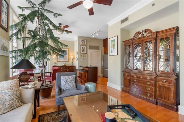 living area with track lighting, wood finished floors, visible vents, and crown molding