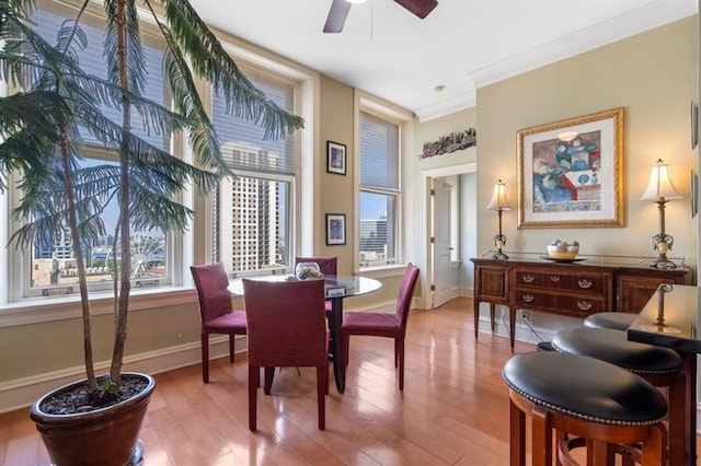 dining room featuring ornamental molding, ceiling fan, baseboards, and wood finished floors