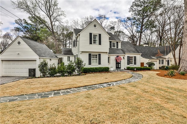 view of front of property featuring a front lawn, driveway, a garage, and a chimney