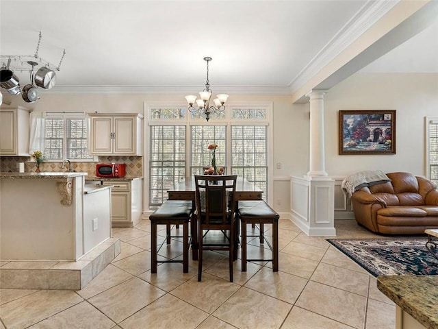 dining space with ornate columns, crown molding, a chandelier, and light tile patterned floors