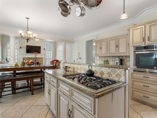 kitchen featuring hanging light fixtures, cream cabinets, decorative backsplash, and stainless steel appliances