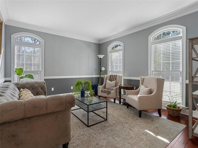 living room featuring wood-type flooring, crown molding, and a healthy amount of sunlight