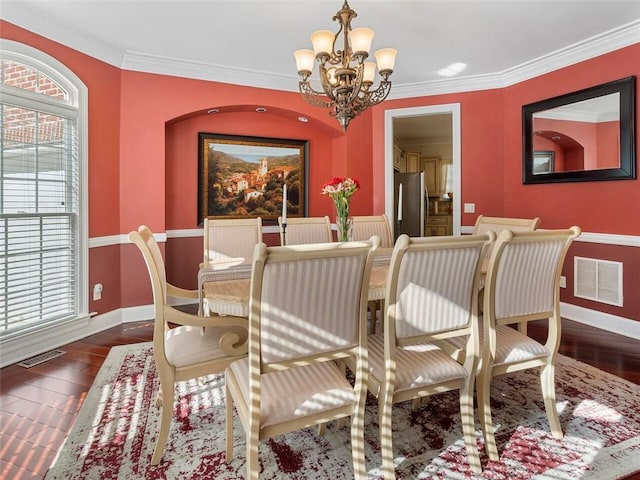 dining area featuring dark hardwood / wood-style floors, crown molding, and a chandelier