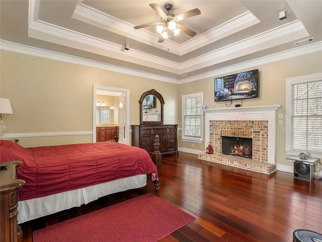 bedroom with ceiling fan, a tray ceiling, ornamental molding, and dark hardwood / wood-style flooring