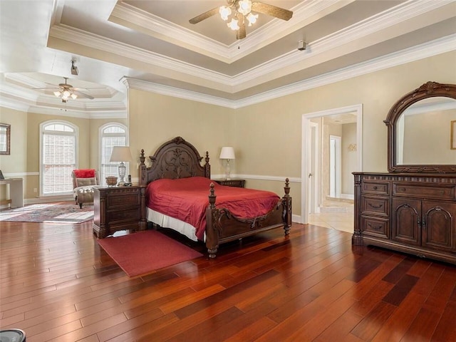 bedroom featuring ornamental molding, ceiling fan, wood-type flooring, and a raised ceiling