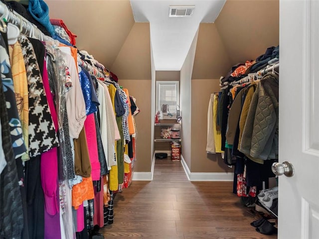 spacious closet with lofted ceiling and dark hardwood / wood-style flooring