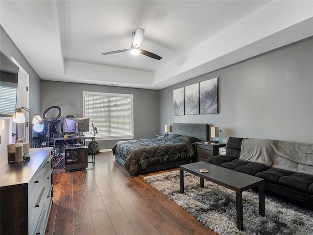 bedroom featuring dark hardwood / wood-style floors, a tray ceiling, and ceiling fan