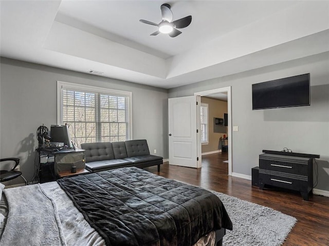 bedroom featuring ceiling fan, a raised ceiling, and dark hardwood / wood-style floors