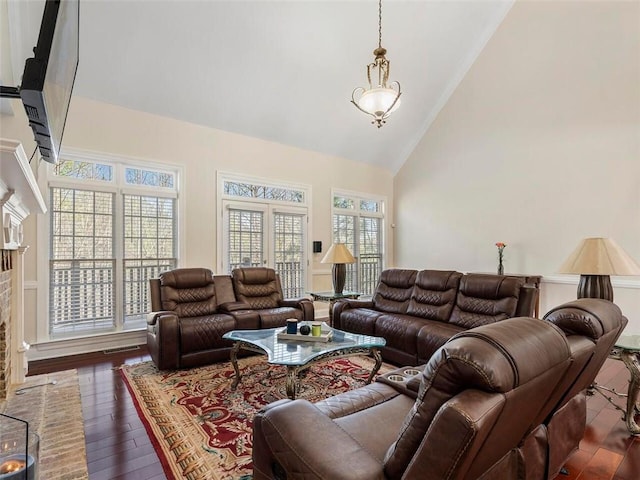 living room with a brick fireplace, high vaulted ceiling, and dark hardwood / wood-style floors