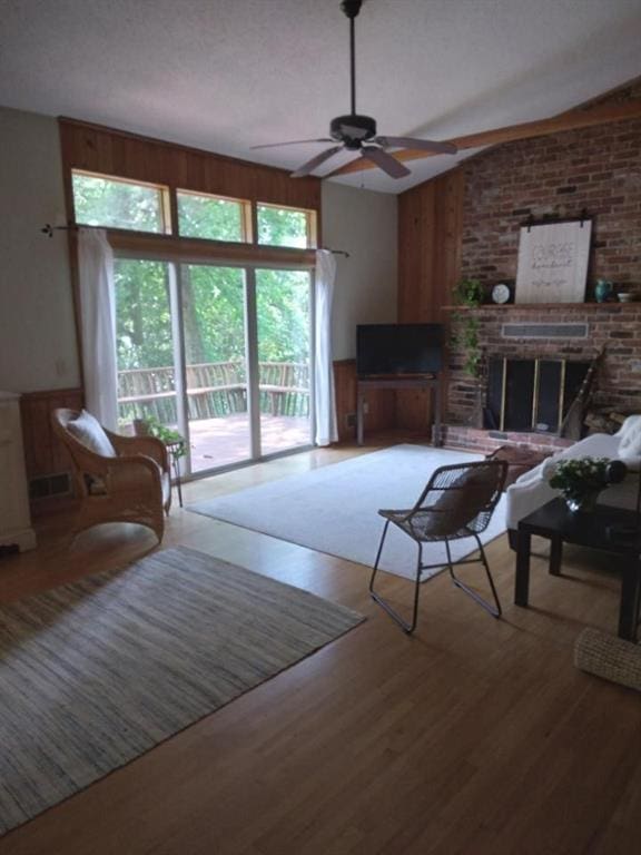 9165 Duran Cir, Gainesville, GA 30506 - living room featuring a ceiling fan, wood finished floors, a fireplace, and wood walls