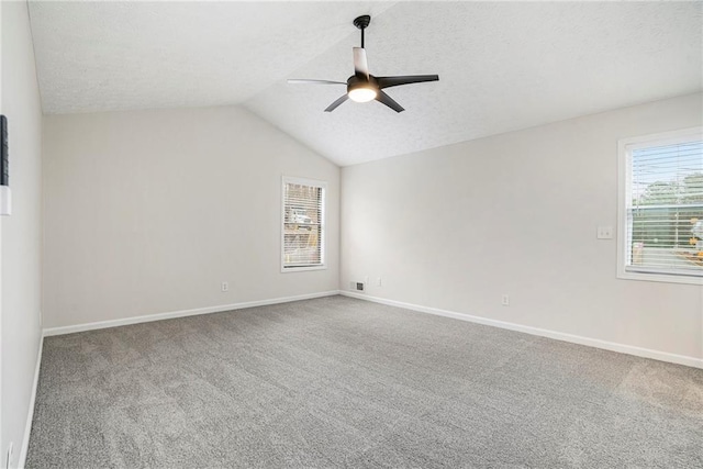 carpeted spare room with lofted ceiling, a textured ceiling, and ceiling fan