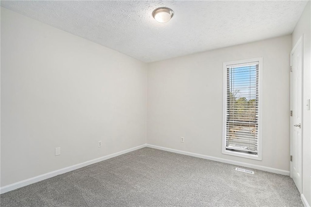 carpeted empty room featuring a textured ceiling