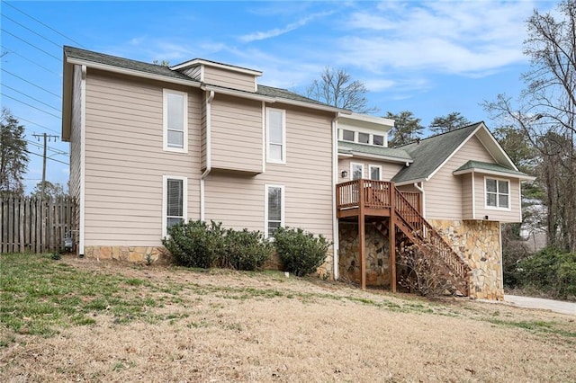 rear view of house with a wooden deck and a lawn