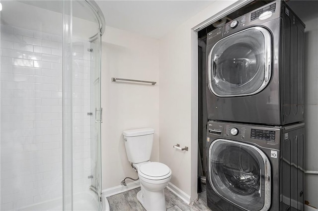 bathroom with walk in shower, toilet, and stacked washer / dryer