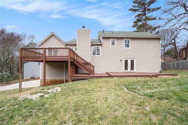 back of property with a wooden deck, a lawn, and french doors