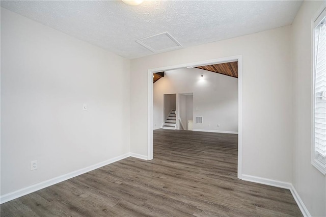 empty room with plenty of natural light, dark hardwood / wood-style flooring, and a textured ceiling