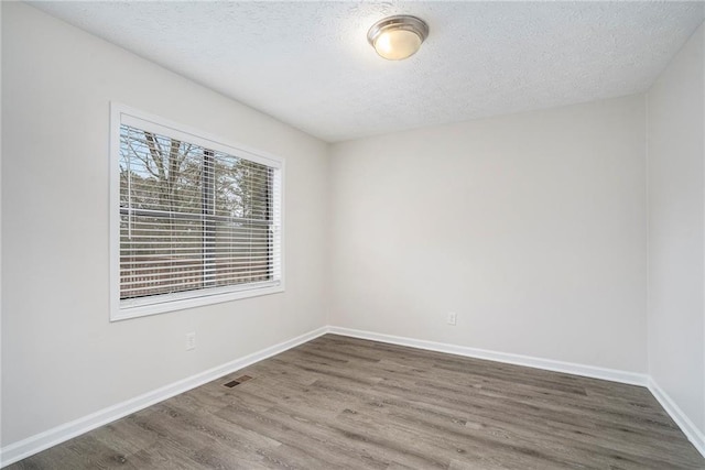 empty room featuring dark wood-type flooring and a textured ceiling