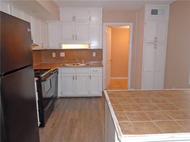 kitchen featuring sink, stainless steel refrigerator, and white cabinets