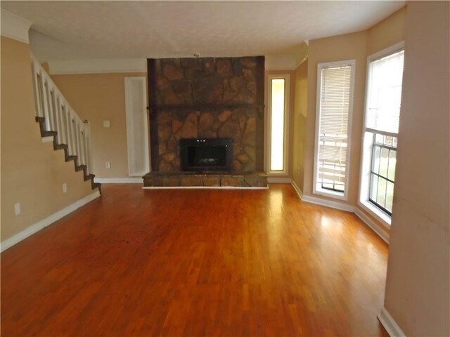 unfurnished living room featuring wood-type flooring and a stone fireplace