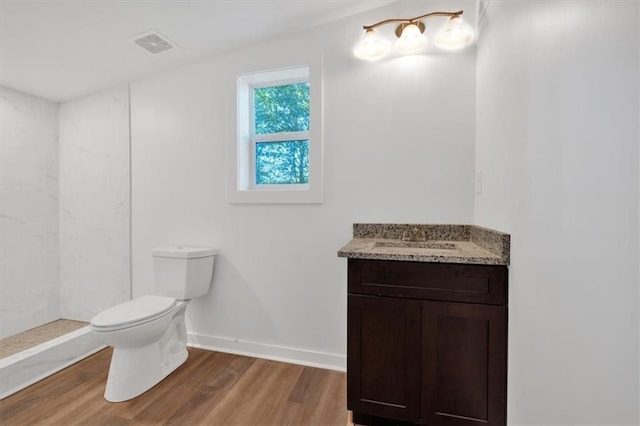 bathroom featuring a shower, vanity, hardwood / wood-style flooring, and toilet