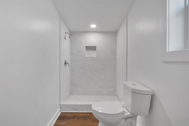 bathroom featuring tiled shower, hardwood / wood-style flooring, and toilet