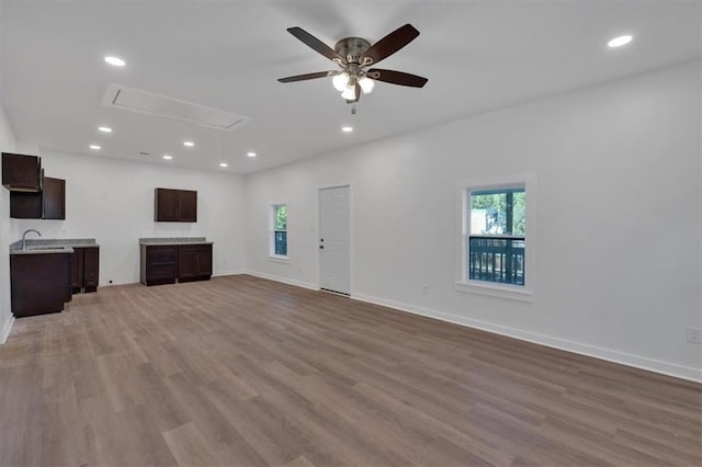 unfurnished living room featuring ceiling fan, sink, and light hardwood / wood-style flooring