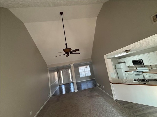 unfurnished living room featuring a sink, high vaulted ceiling, carpet flooring, and baseboards