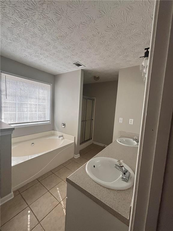 bathroom with a stall shower, visible vents, tile patterned floors, a garden tub, and a sink