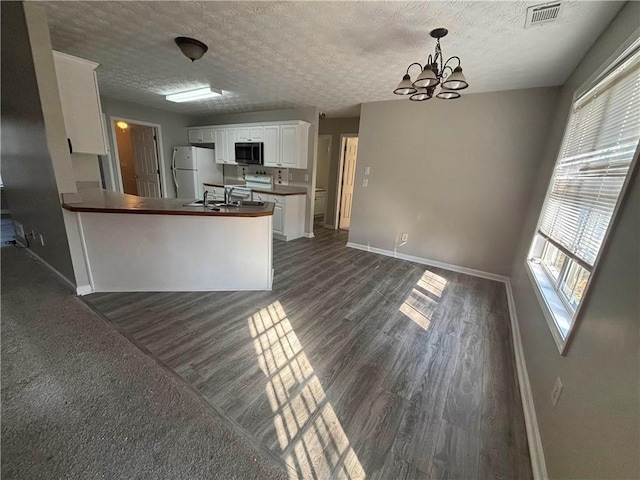 kitchen with baseboards, visible vents, white cabinets, dark wood-style floors, and freestanding refrigerator