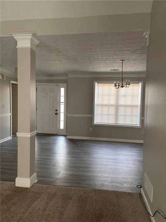 entrance foyer featuring a textured ceiling, dark wood-style floors, decorative columns, and baseboards