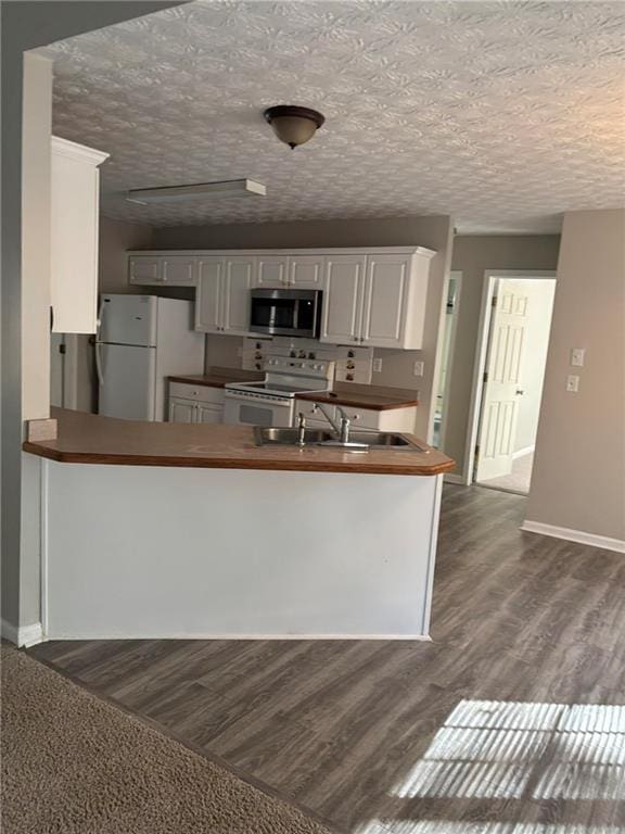 kitchen with a sink, white appliances, white cabinets, and dark wood-style flooring