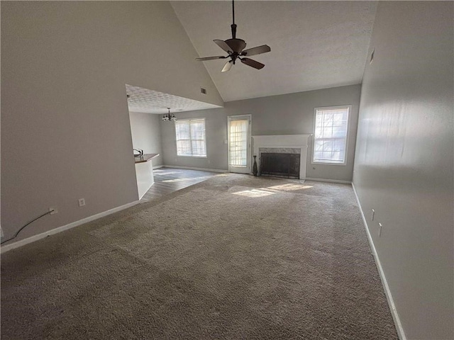 unfurnished living room featuring a healthy amount of sunlight, high vaulted ceiling, carpet flooring, and a high end fireplace