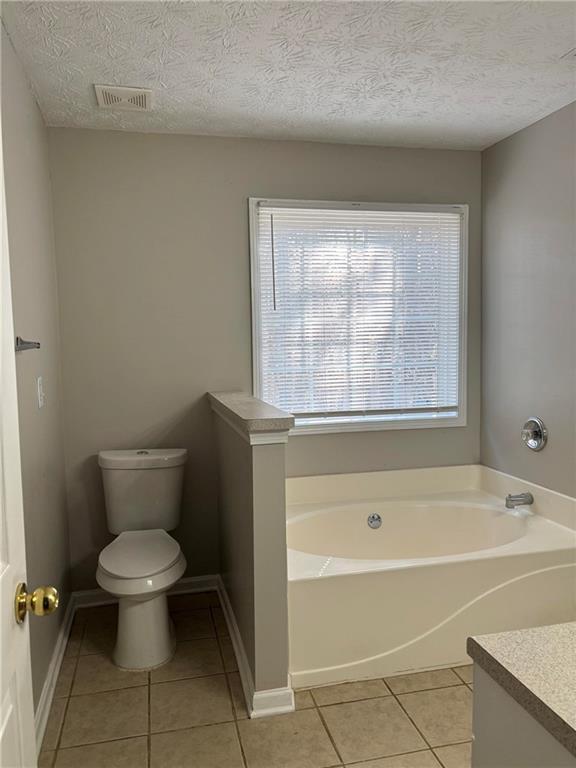 full bathroom with visible vents, toilet, a garden tub, tile patterned flooring, and vanity